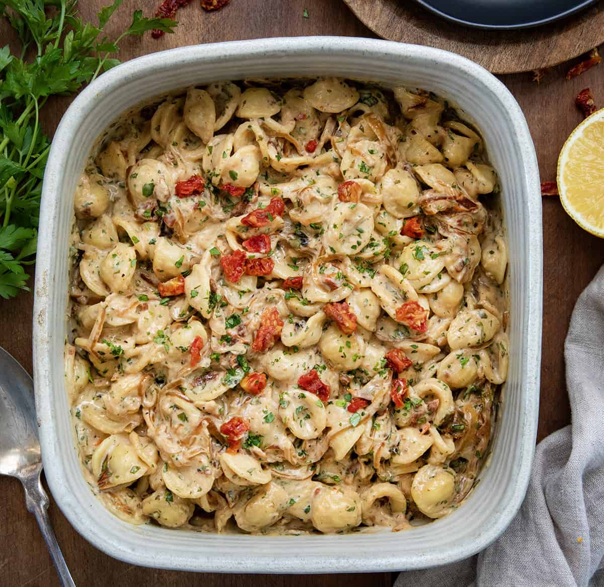 Ceramic casserole dish with Caramelized Onion Pasta in it on a wooden table from overhead.