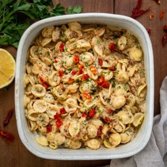 Ceramic casserole dish with Caramelized Onion Pasta in it on a wooden table from overhead.