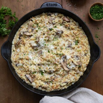 Skillet of Creamy Mushroom Orzo on a wooden table from overhead.