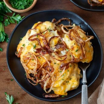 Plates of Fried Onion Scalloped Potatoes on a wooden table from overhead.