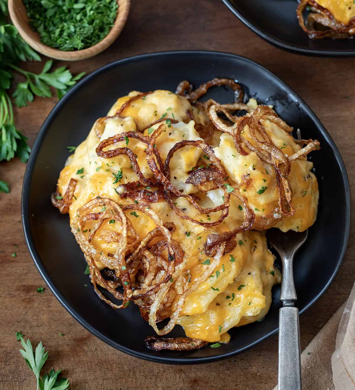 Plates of Fried Onion Scalloped Potatoes on a wooden table from overhead.