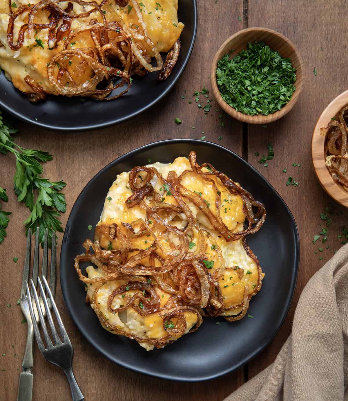 Plates of Fried Onion Scalloped Potatoes on a wooden table from overhead.