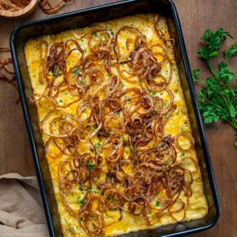 Pan of Fried Onion Scalloped Potatoes on a wooden table from overhead.