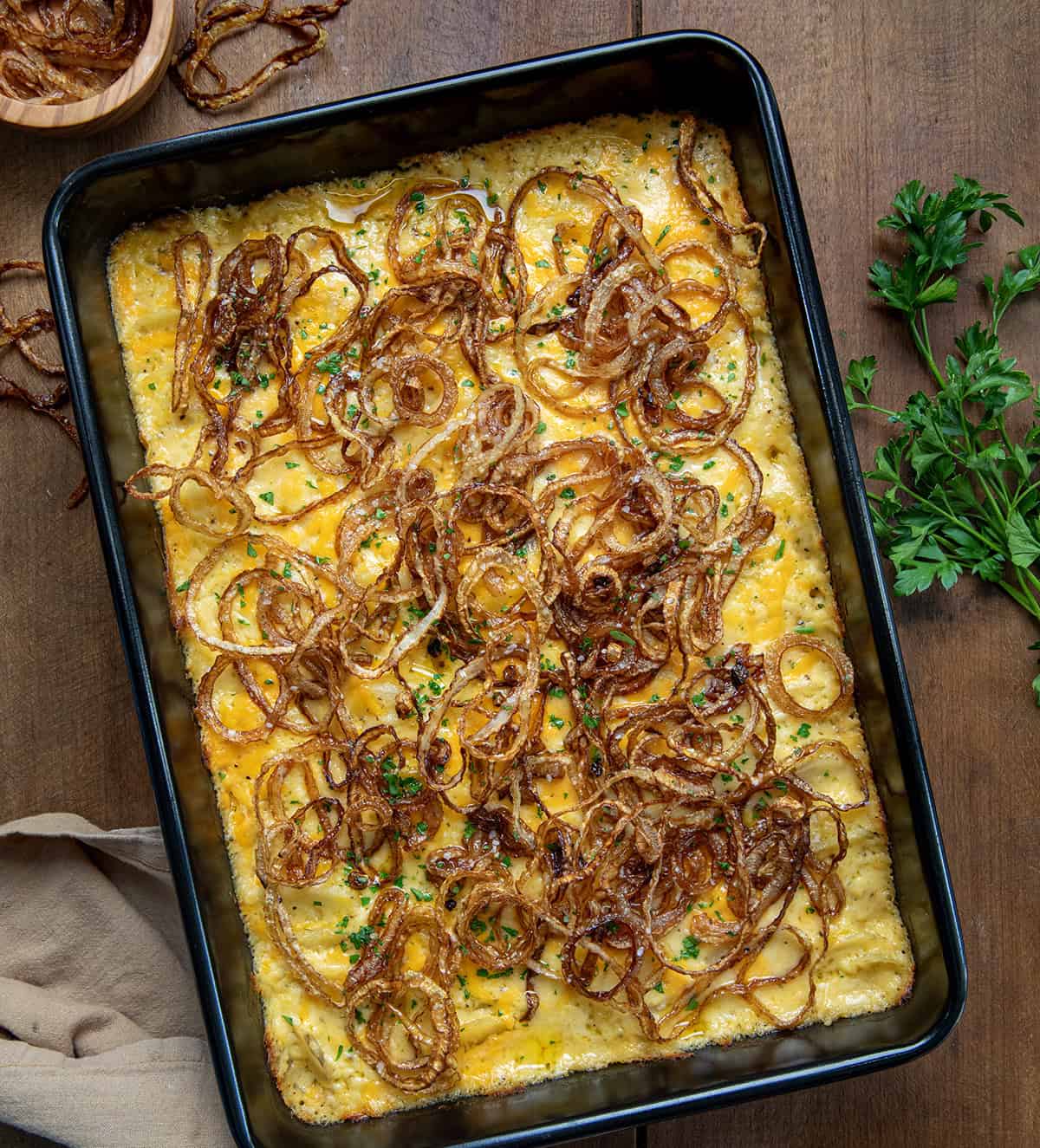 Pan of Fried Onion Scalloped Potatoes on a wooden table from overhead.