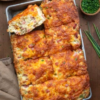 Pan of Ham and Cheese Butter Swim Biscuits with one biscuit on its side on a wooden table from overhead.