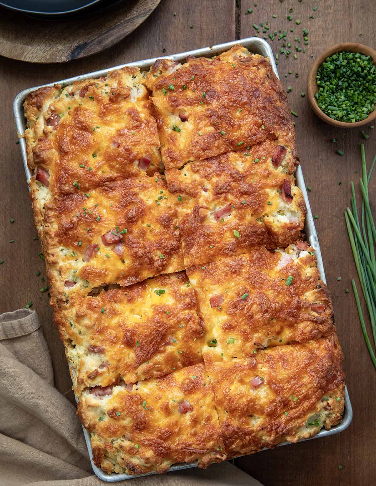 Ham and Cheese Butter Swim Biscuits in a pan and cut into pieces on a wooden table. 