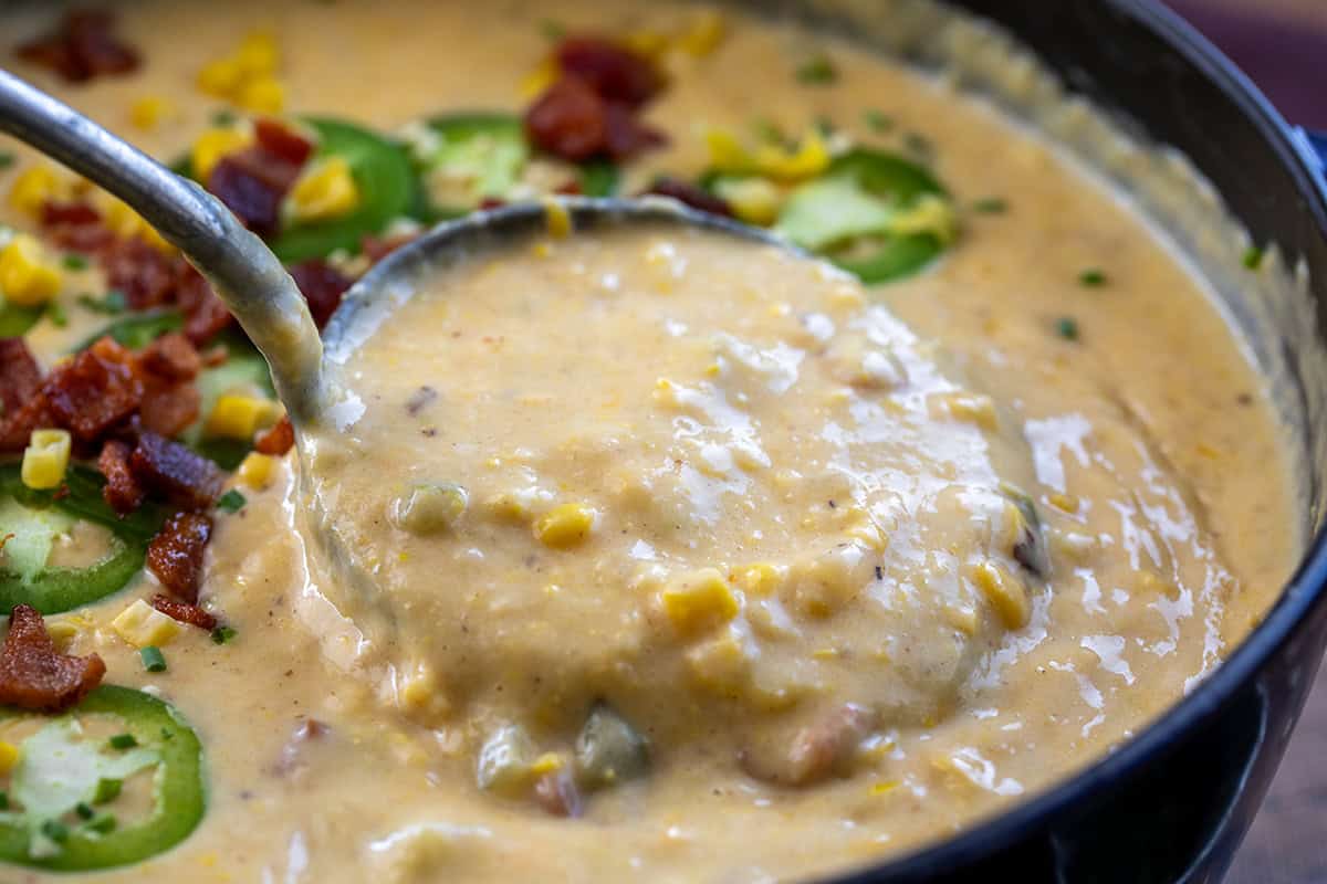 Scooping Jalapeno Popper Corn Chowder from a pot very close up.