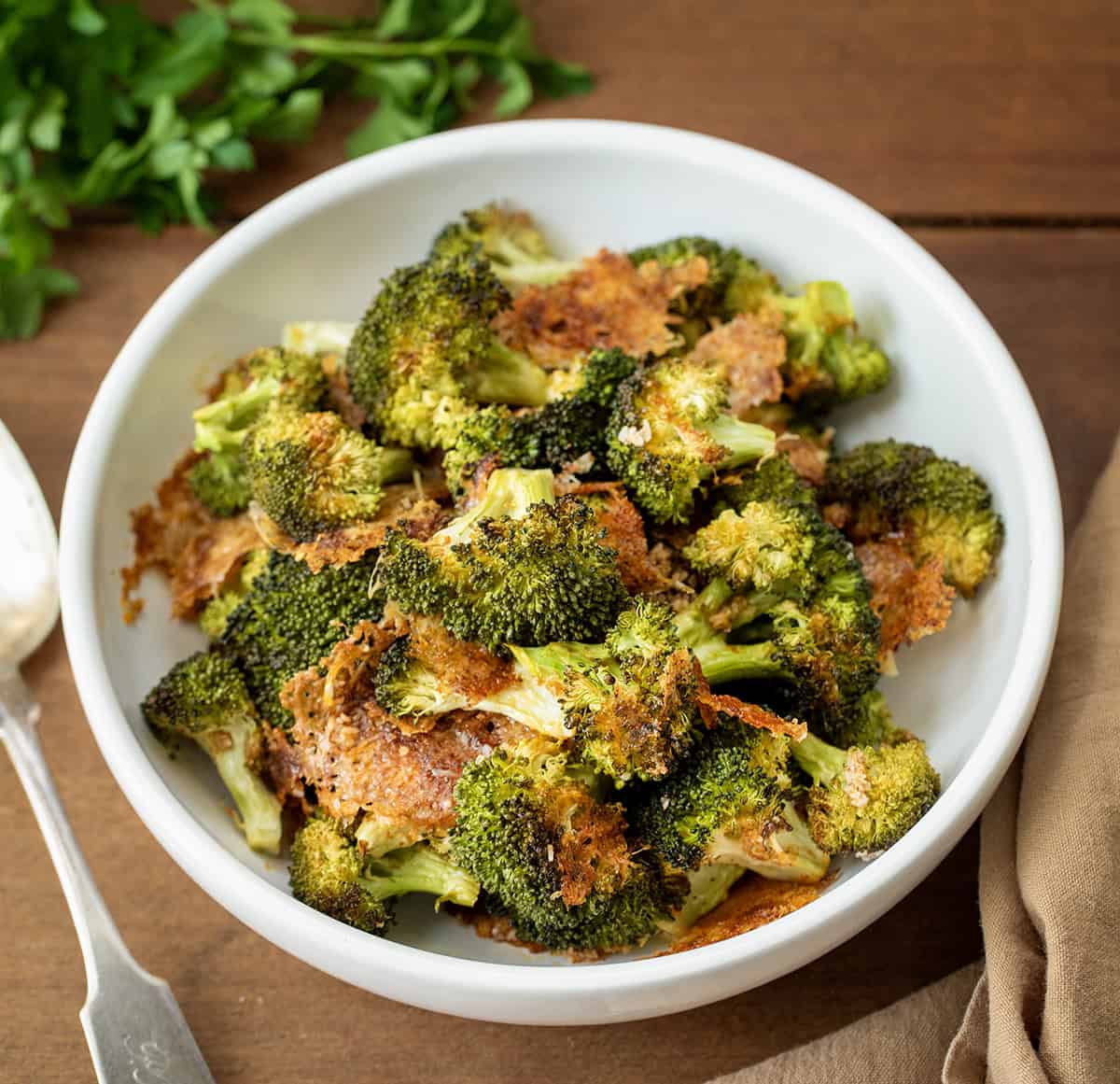 Bowl of Parmesan Crusted Broccoli on a wooden table.