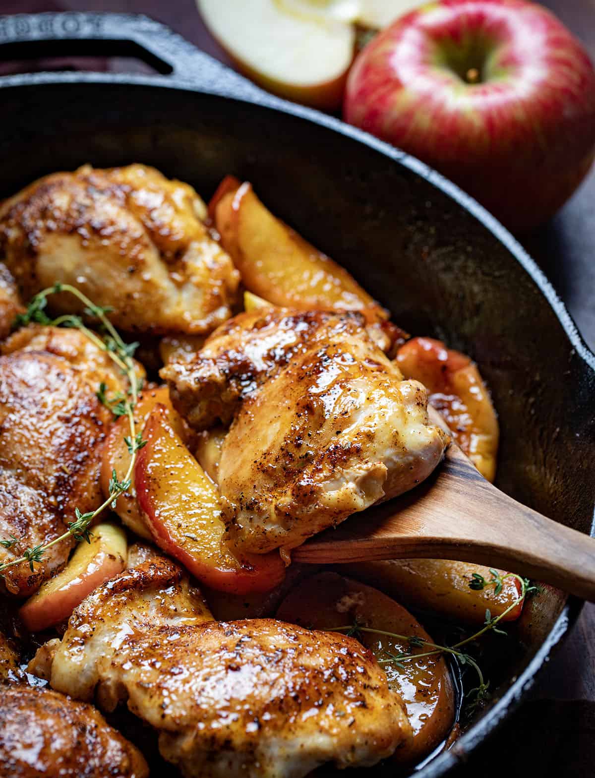 Picking up a pice of chicken from a skillet with a wooden spoon.