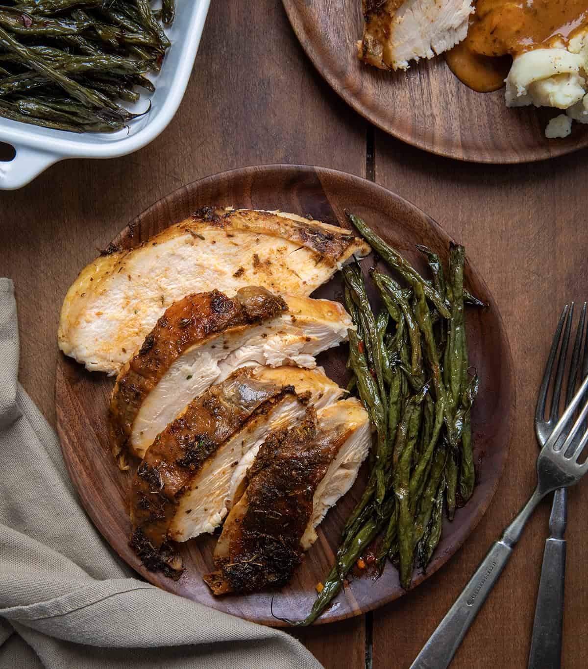 Slices of Cajun Dry Brine Turkey on a wooden plate from overhead.