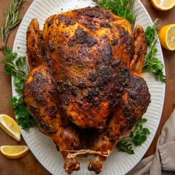 Whole Cajun Dry Brine Turkey on a platter on a wooden table fro overhead.