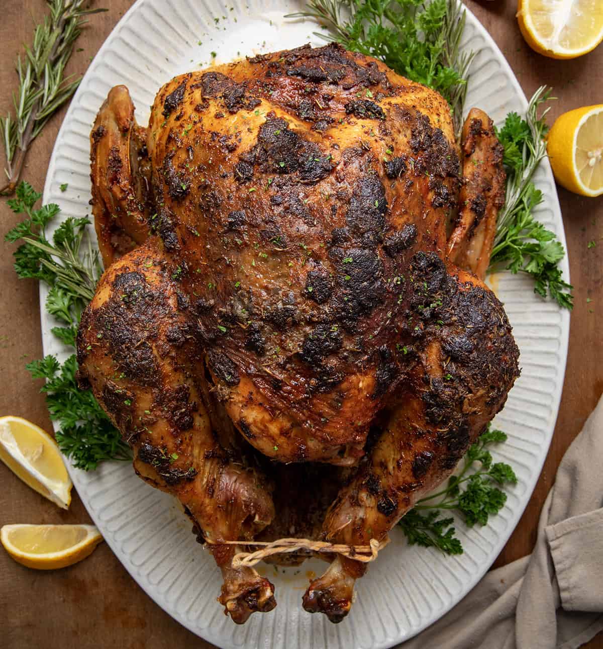 Whole Cajun Dry Brine Turkey on a platter on a wooden table fro overhead. 