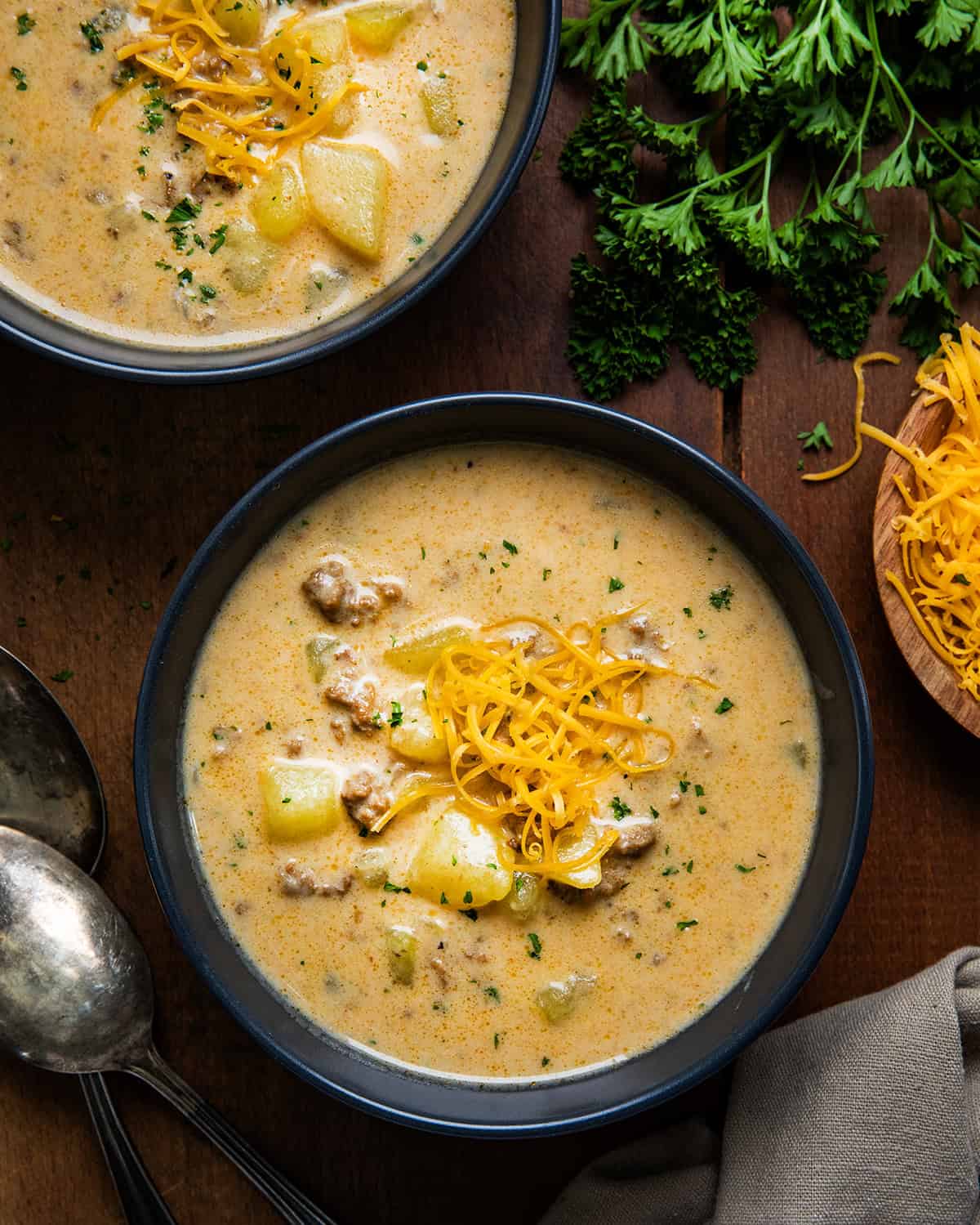 Black bowls filled with Cheesy Beef and Potato Soup on a wooden table from overhead.