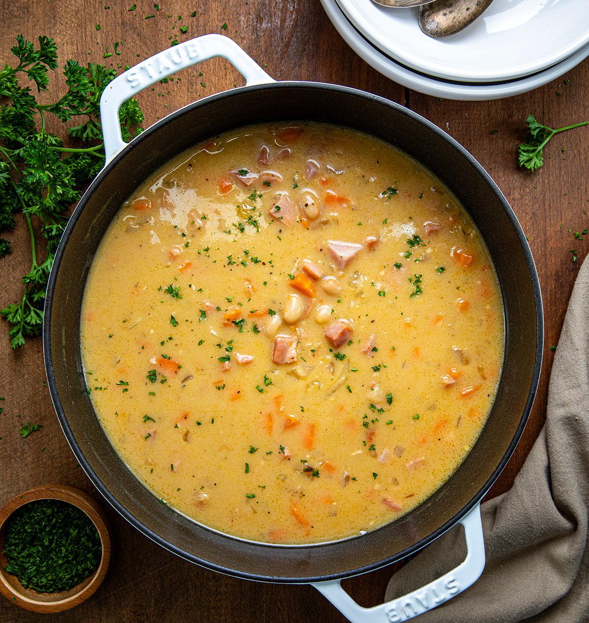 Pot of Cheesy Ham and Bean Soup on a wooden table from overhead. 