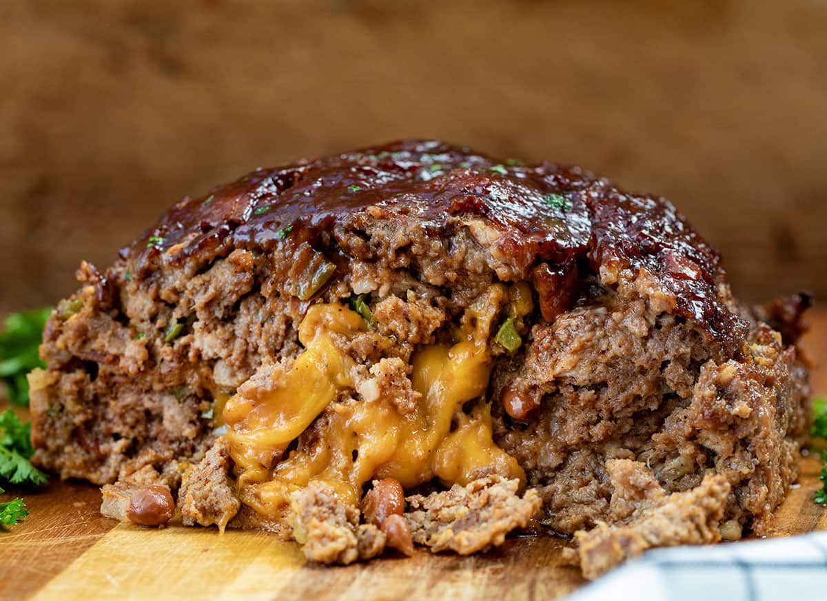 CLose up of a loaf of Cowboy Meatloaf showing melted cheese spilling out.