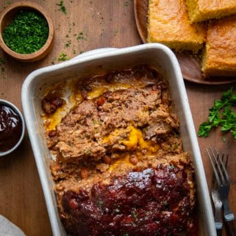 Slice of Cowboy Meatloaf laying flat in the pan with remaining meatloaf from overhead.