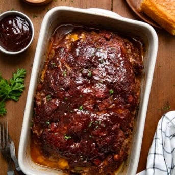 Whole Cowboy Meatloaf in a pan on a wooden table from overhead.