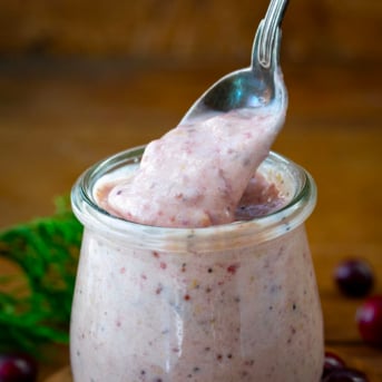 Spoon picking up some Cranberry Aioli from a jar.