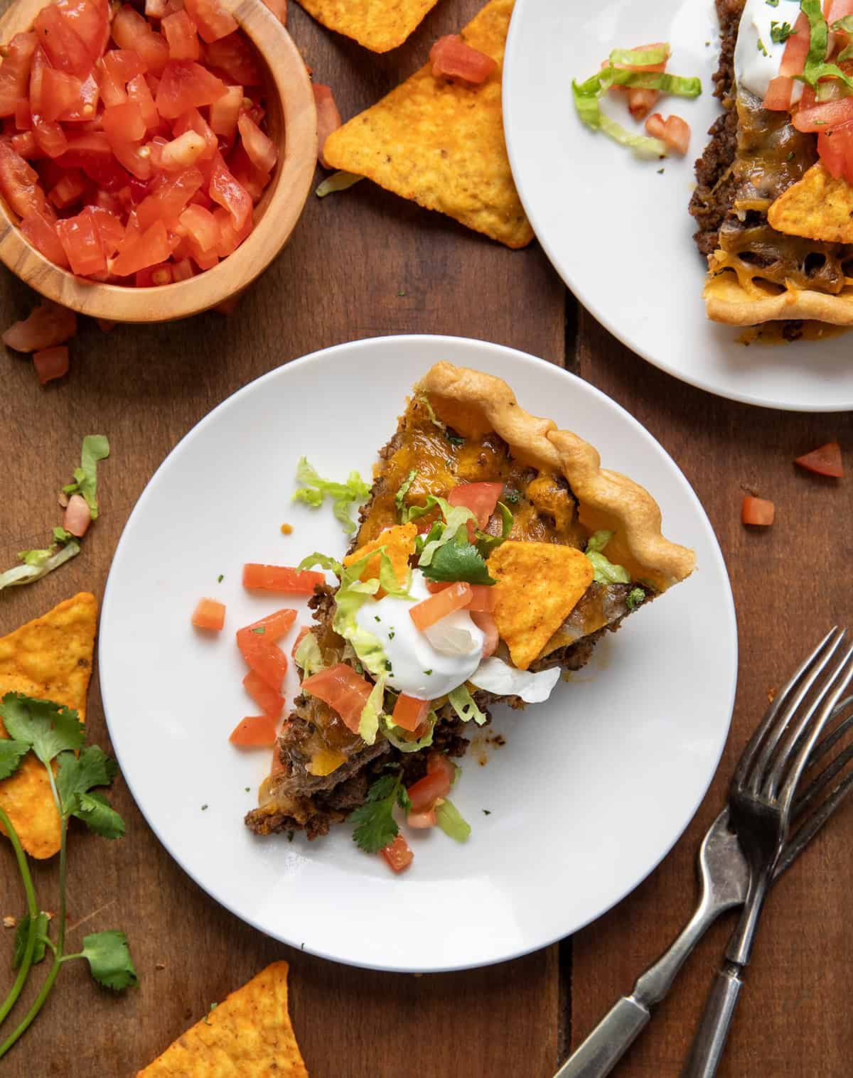 Slices of Dorito Taco Pie on white plates on a wooden table from overhead.