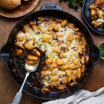 Skillet of French Onion Gnocchi with a portion of removed and spoon left in the pan shot from overhead.