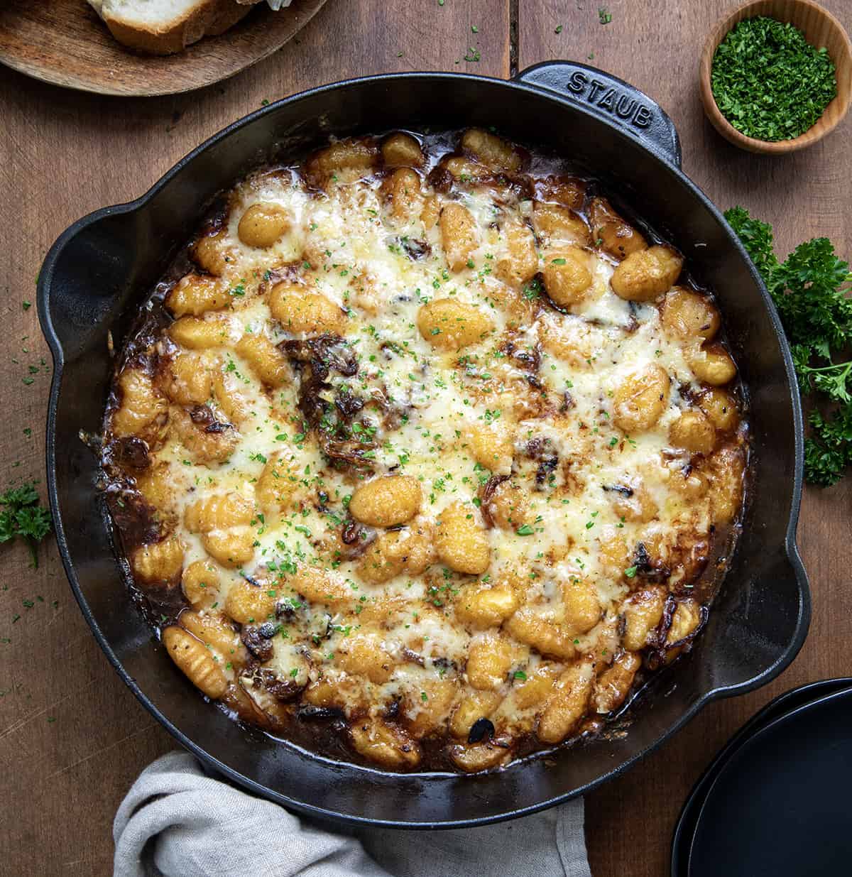 Skillet of French Onion Gnocchi on a wooden table from overhead. 