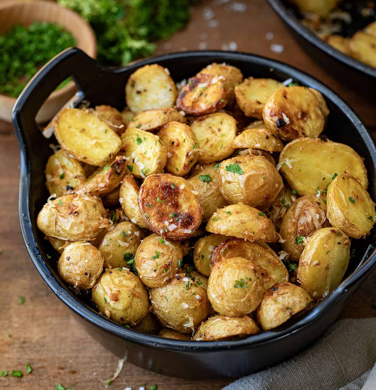 Bowl of Garlic Parmesan Roasted Potatoes on a wooden table.