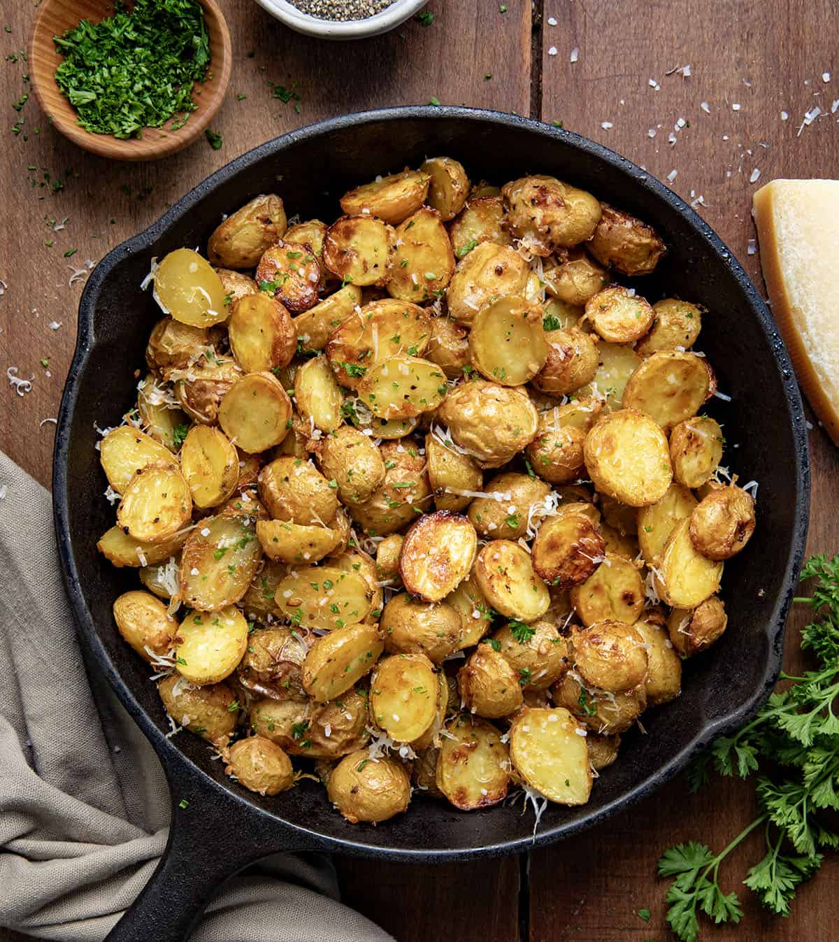 Skillet of Garlic Parmesan Roasted Potatoes on a wooden table from overhead.