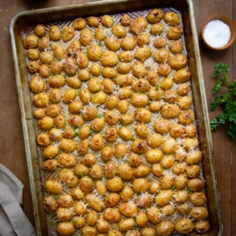 Pan of Garlic Parmesan Roasted Potatoes on a wooden table from overhead.