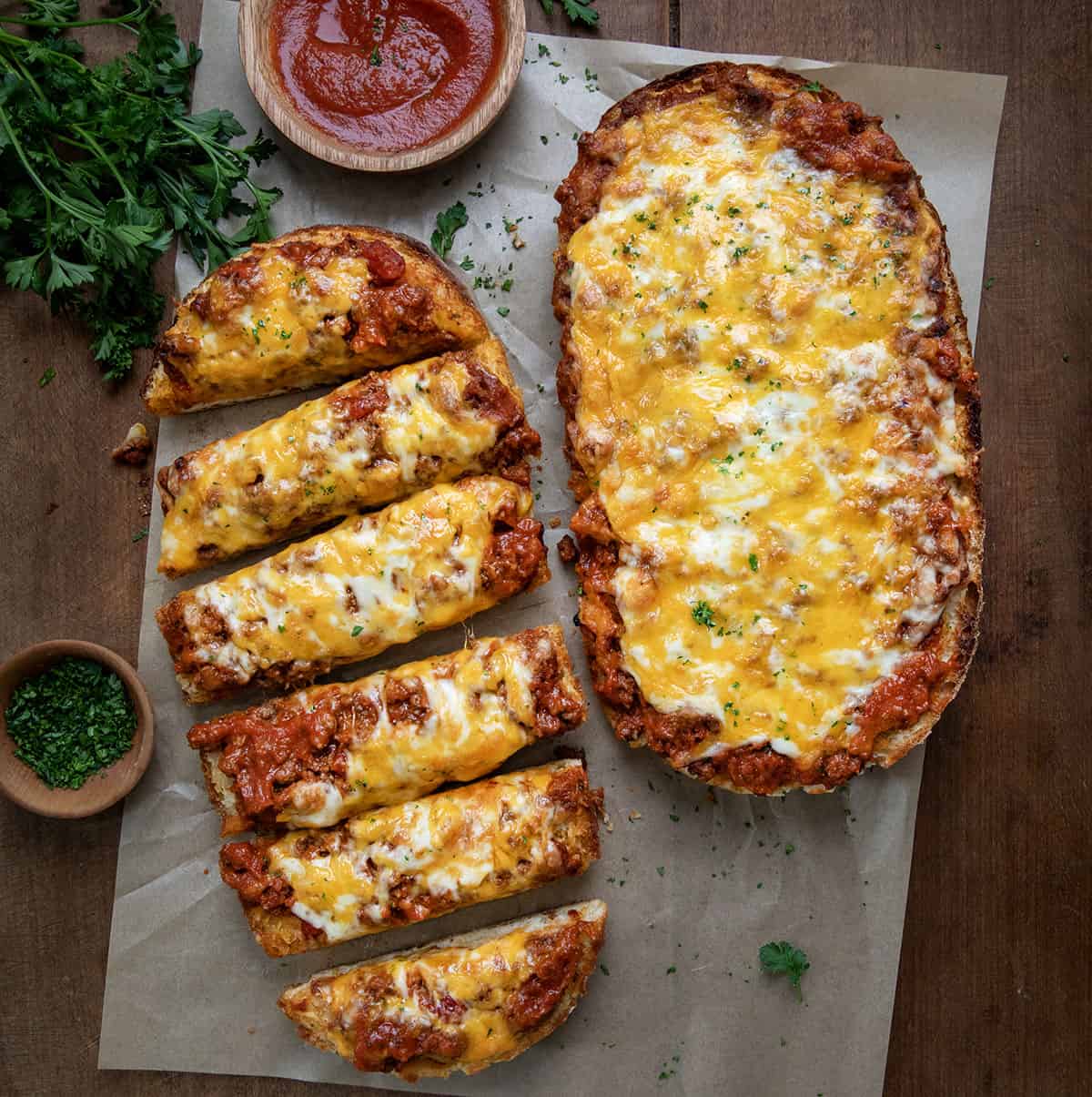 Lasagna Garlic Bread on a wooden table with one cut into slices. 