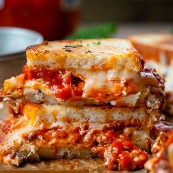 Lasagna Grilled Cheese sandwich cut in half and showing meat and cheese spilling out.