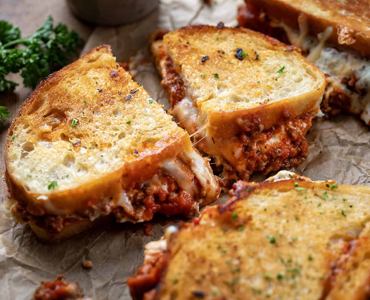 Cut in half Lasagna Grilled Cheese on a piece of parchment paper and cut in half.