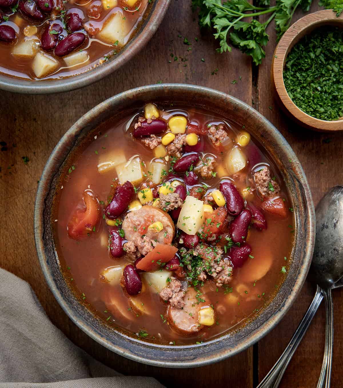 Bowls of Slow Cooker Cowboy Soup on a wooden table from overhead.