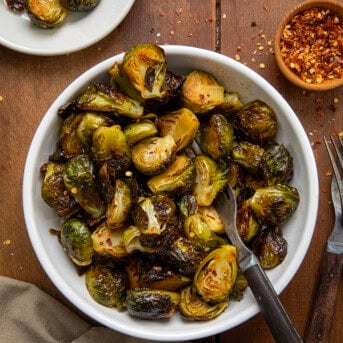 Bowl of Sweet Sriracha Brussels Sprouts with a fork in it on a wooden table from overhead.