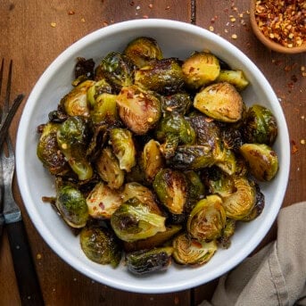 Bowl of Sweet Sriracha Brussels Sprouts on a wooden table from overhead.