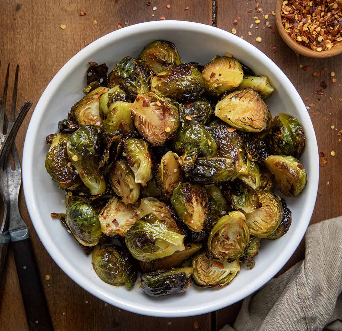 Bowl of Sweet Sriracha Brussels Sprouts on a wooden table from overhead.