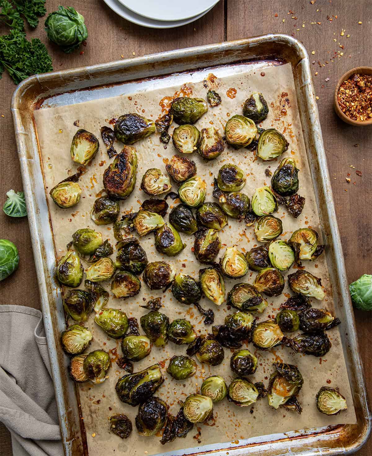 Sheet pan of Sweet Sriracha Brussels Sprouts on a wooden table from overhead.