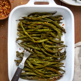 Tray of Sweet and Spicy Green Beans on a wooden table from overhead.