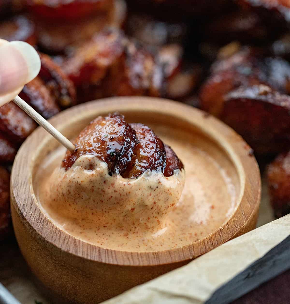 Dipping a Chipotle Aioli Hasselback Kielbasa Bite into Chipotle sauce.