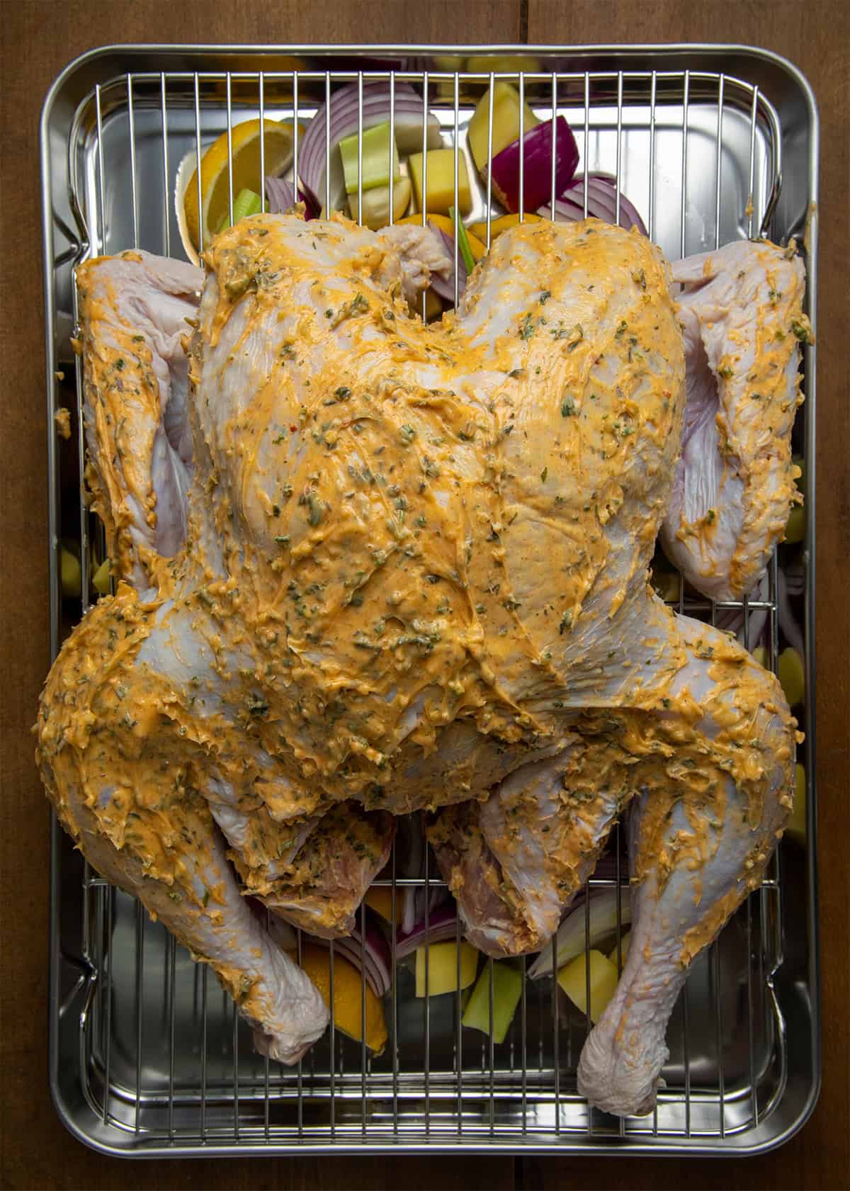 Whole uncooked Cowboy Butter Turkey on a platter on a wooden table from overhead before going into oven.