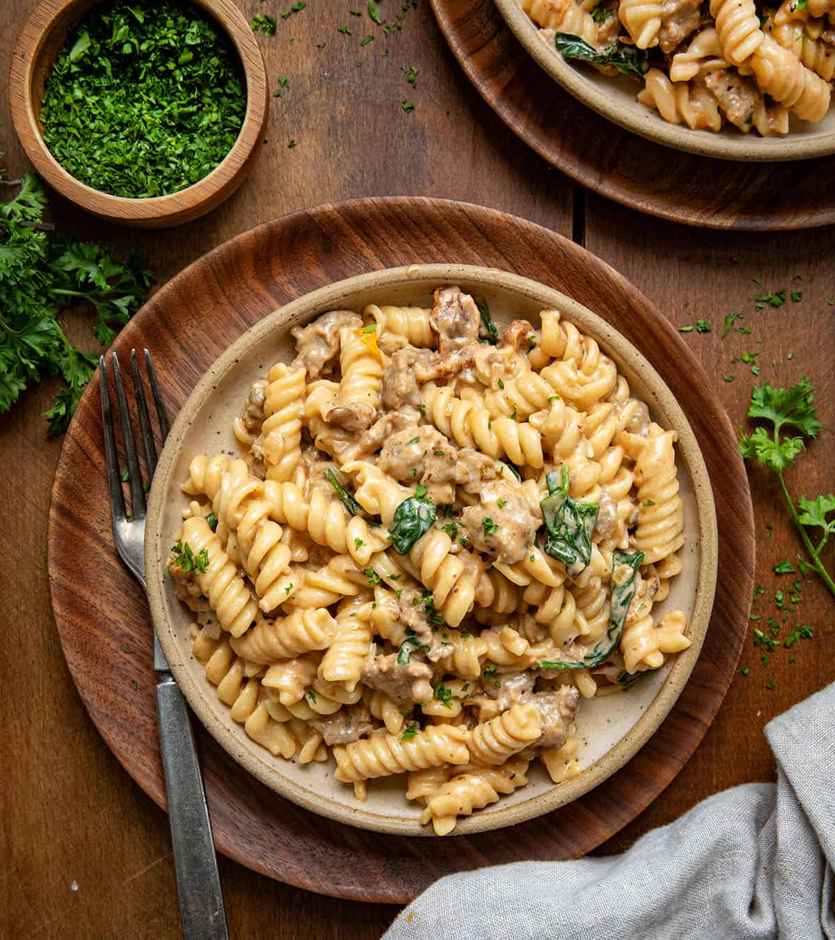 Plates of Creamy Italian Sausage Pasta on a wooden table from overhead.