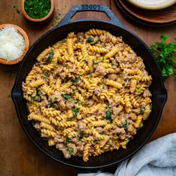 Creamy Italian Sausage Pasta in a skillet on a wooden table from overhead.