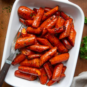 Pan of Honey Balsamic Roasted Carrots with a fork on a wooden table from overhead.