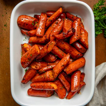 White pan of Honey Balsamic Roasted Carrots on a wooden table from overhead.