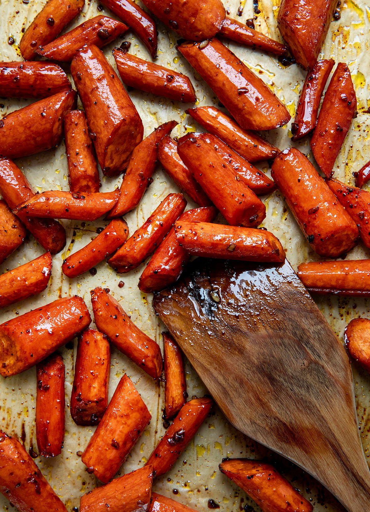 Honey Balsamic Roasted Carrots on a tray with a wooden spoon.