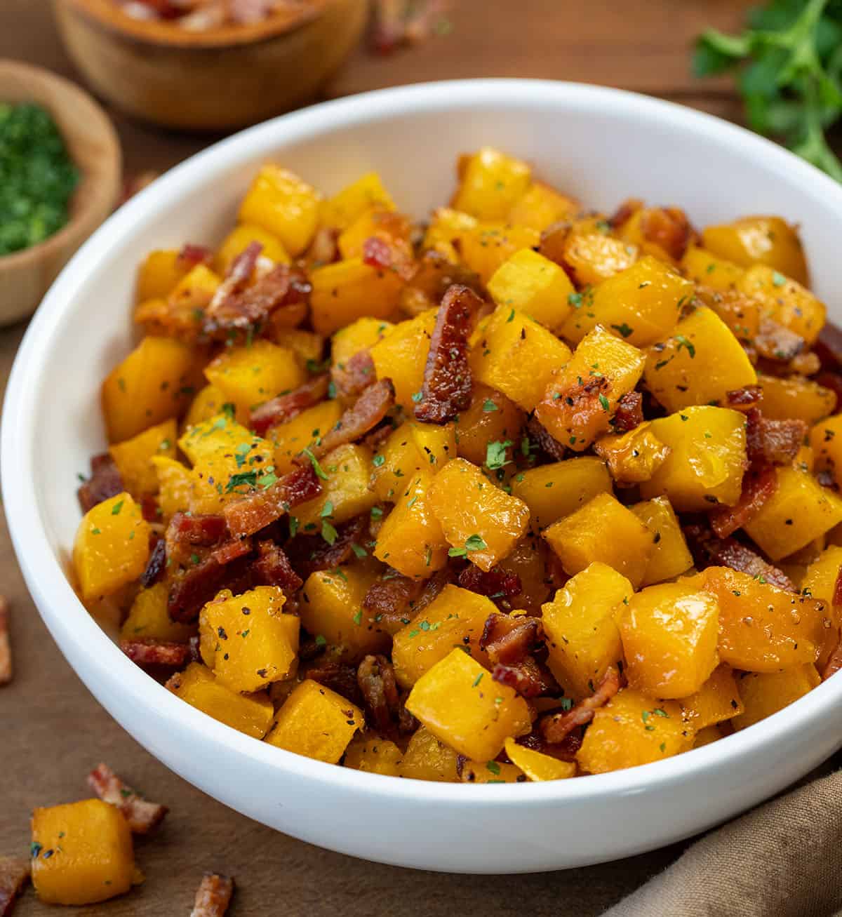 Bowl of Maple Bacon Butternut Squash on a wooden table.