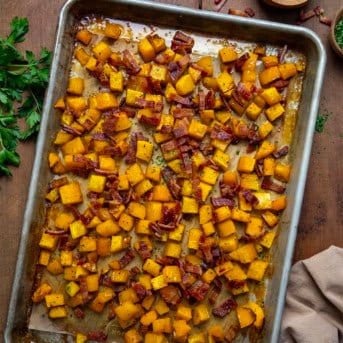 Sheet pan of Maple Bacon Butternut Squash on a wooden table from overhead.