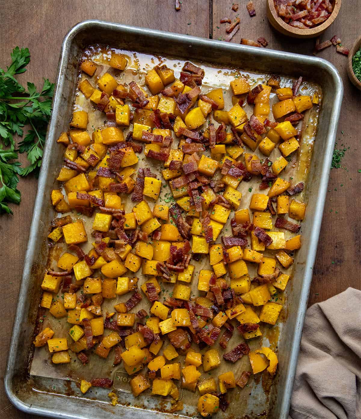 Sheet pan of Maple Bacon Butternut Squash on a wooden table from overhead.