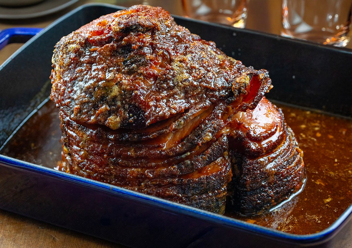 Maple Bourbon Glazed Ham in baking pan on a wooden table.