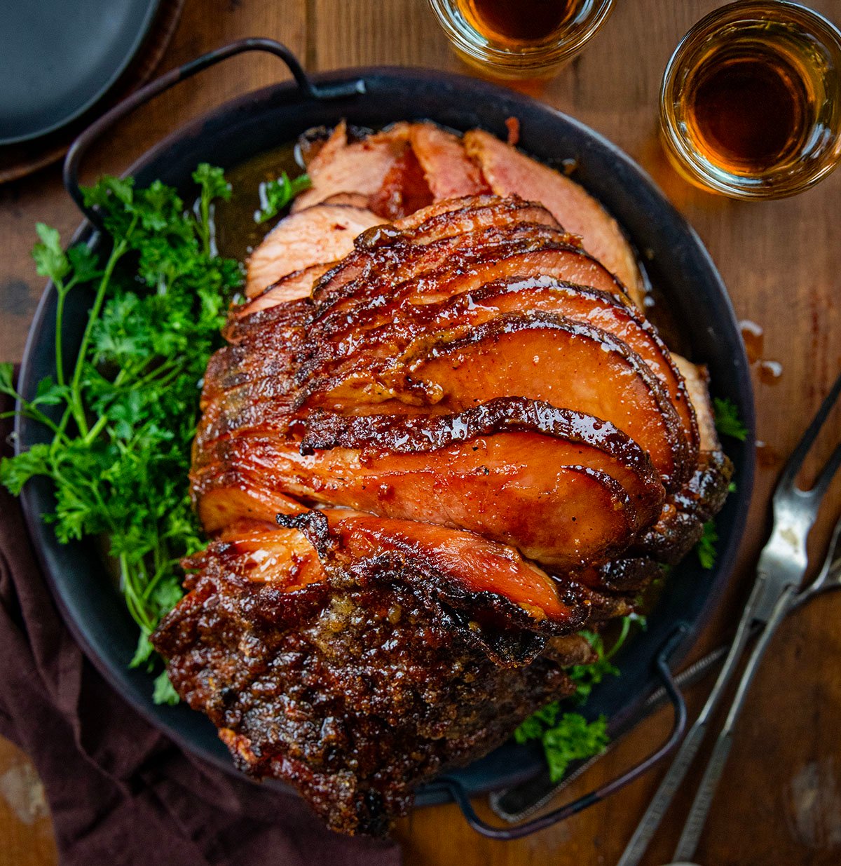 Whole Spiral Maple Bourbon Glazed Ham on a platter on a wooden table from overhead.