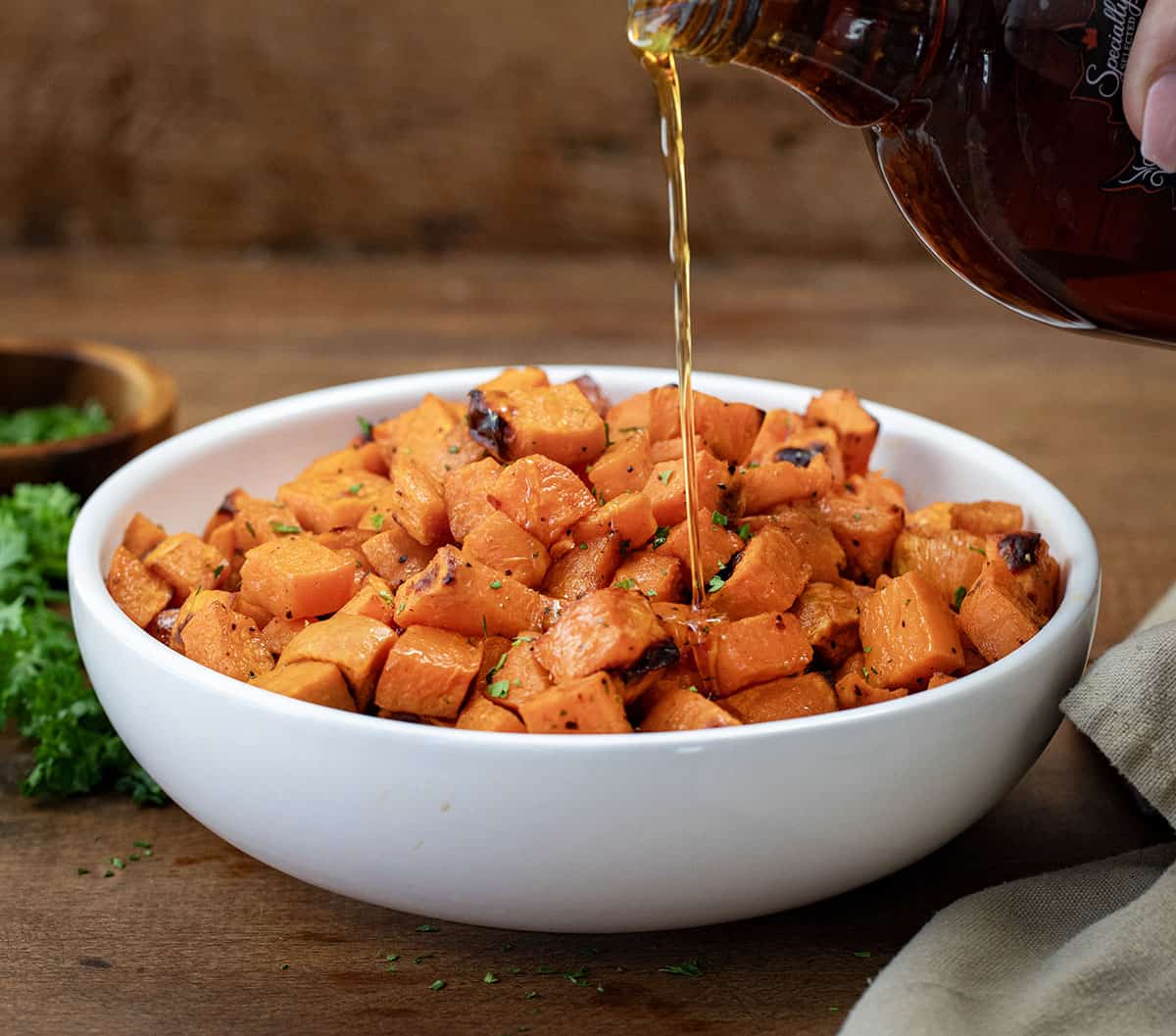 Drizzling syrup over Maple Chipotle Roasted Sweet Potatoes.